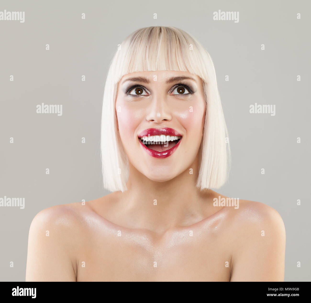 Beautiful blonde woman with bob hairstyle surprised and shocked looks up. Expressive facial expressions Stock Photo