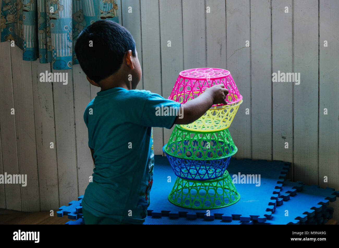 Boy playing to form a tower with plastic baskets Stock Photo
