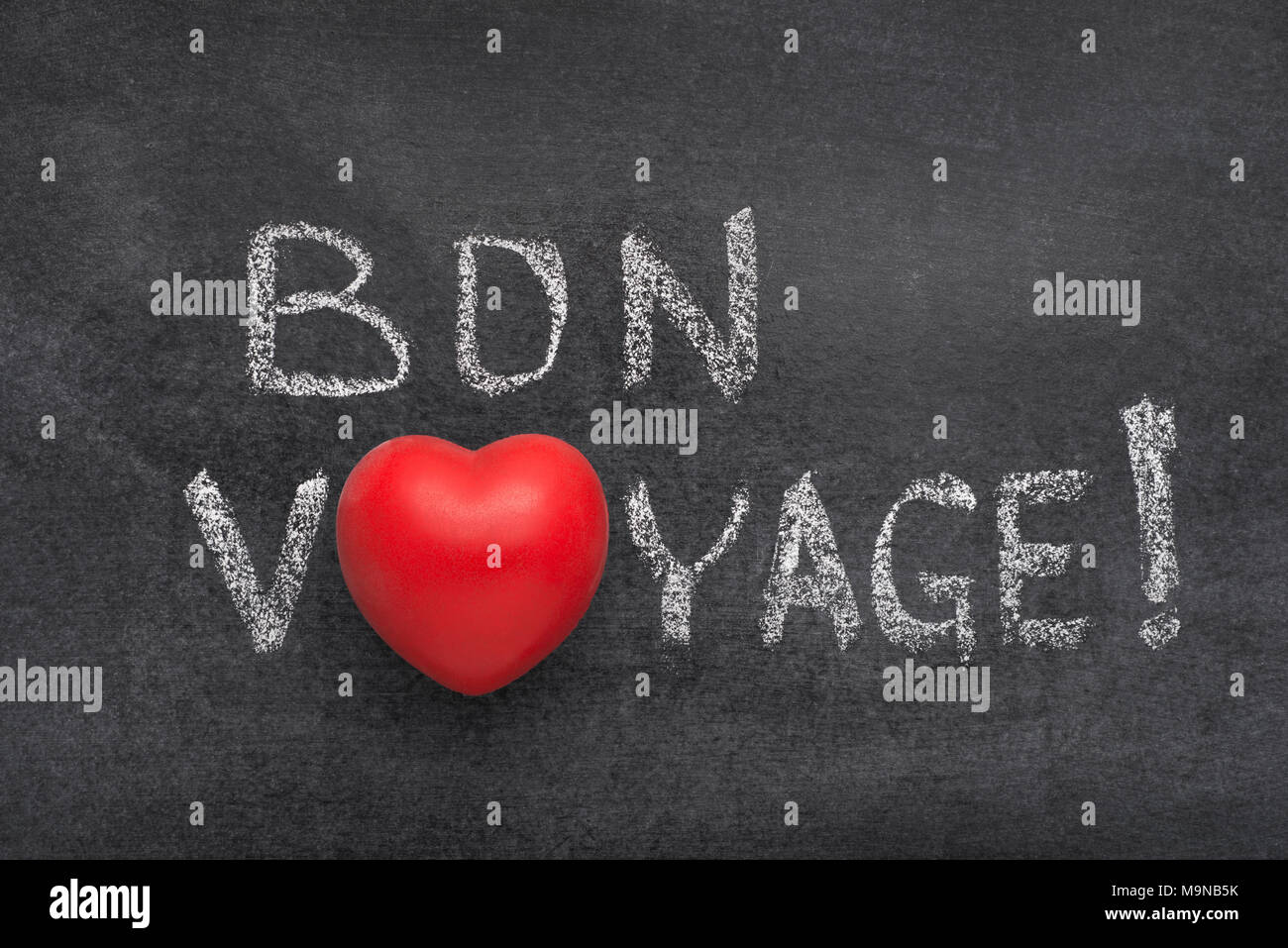 bon voyage exclamation (have a nice trip in French) handwritten on blackboard with heart symbol instead of O Stock Photo