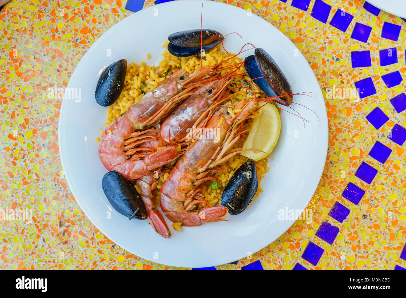 paella portion, rice with tiger shrimps, mussels and lemon Stock Photo