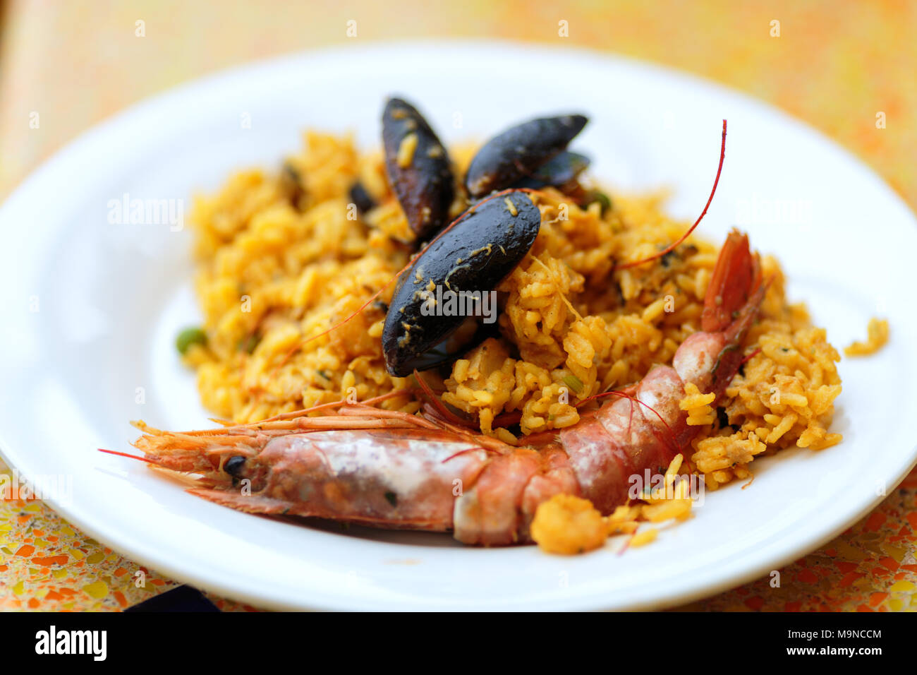 paella portion, rice with tiger shrimps, mussels and lemon Stock Photo