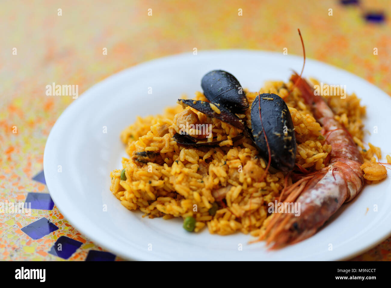 paella portion, rice with tiger shrimps, mussels and lemon Stock Photo