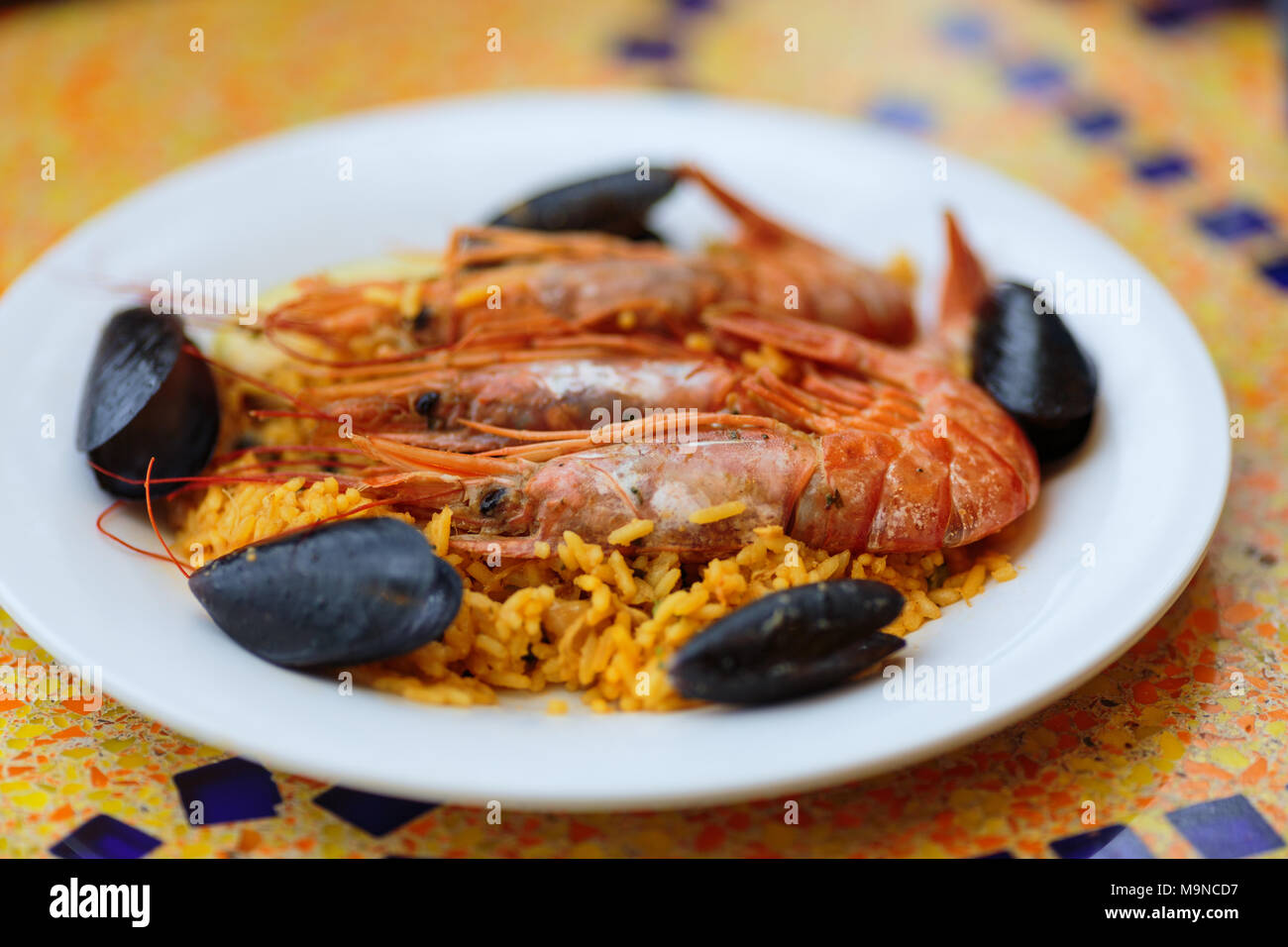 paella portion, rice with tiger shrimps, mussels and lemon Stock Photo
