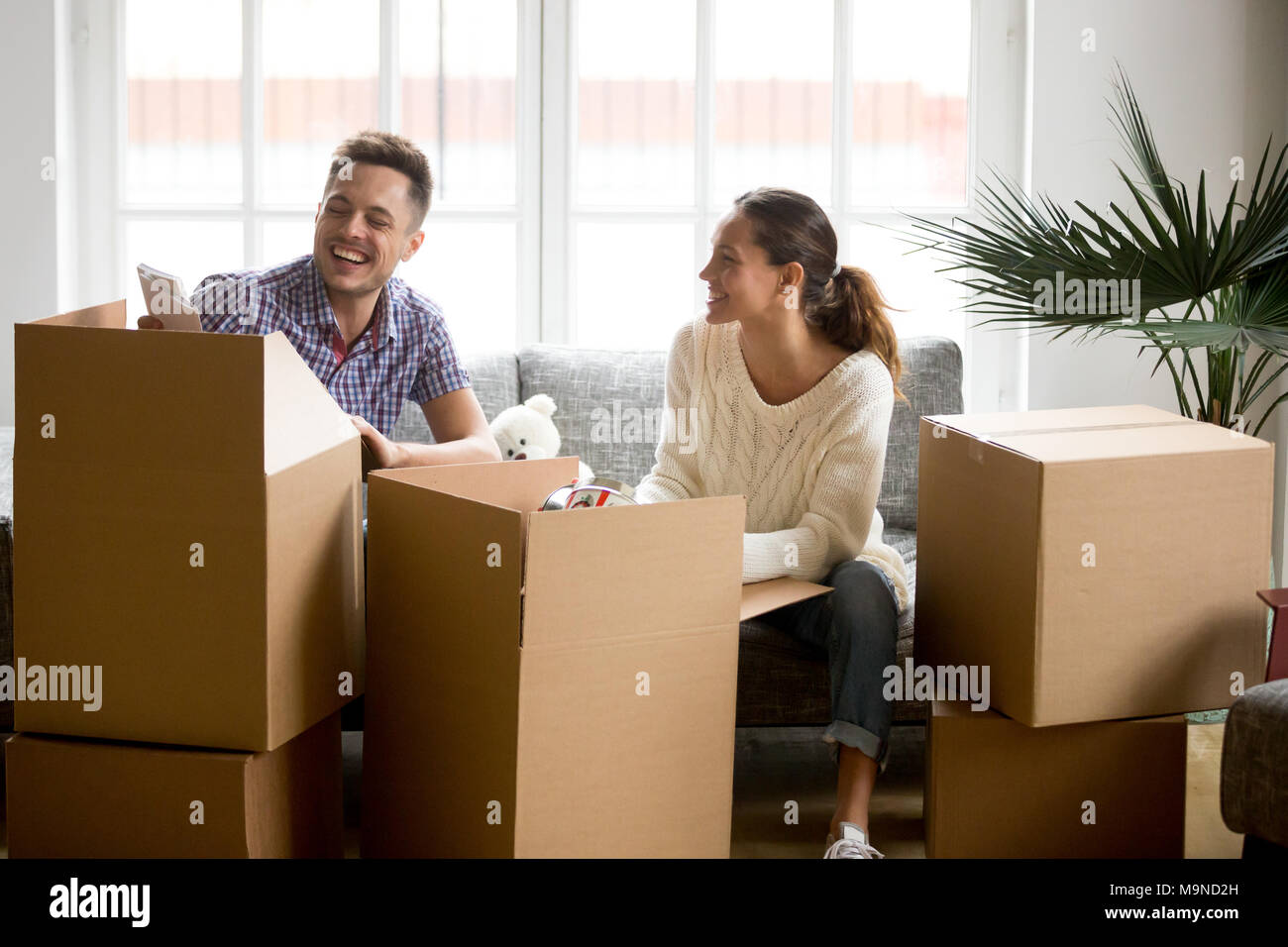 Happy couple having fun and laughing while unpacking boxes on moving ...