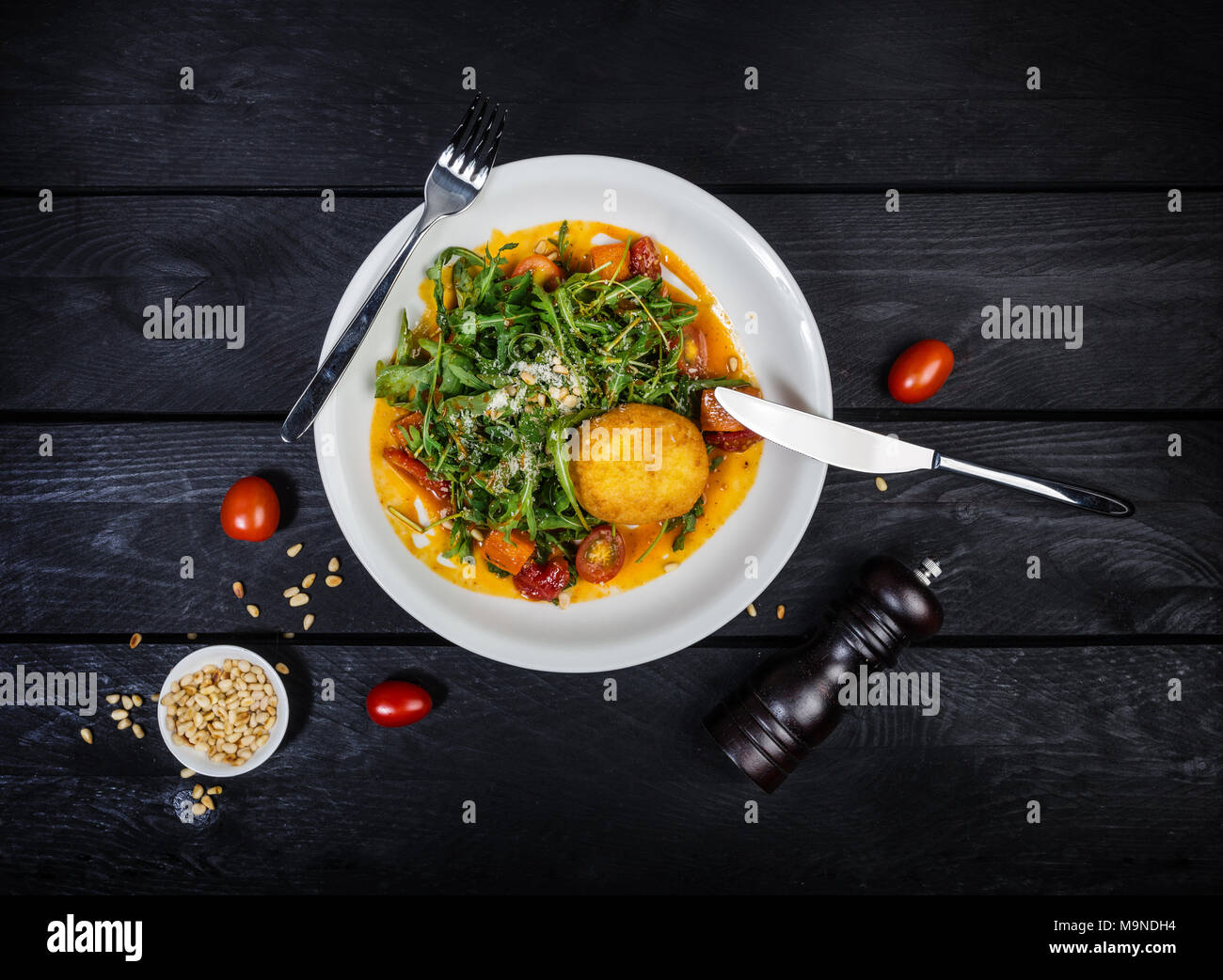 Arugula salad with baked pumpkin and pine nuts in the sea-buckthorn sauce. Stock Photo