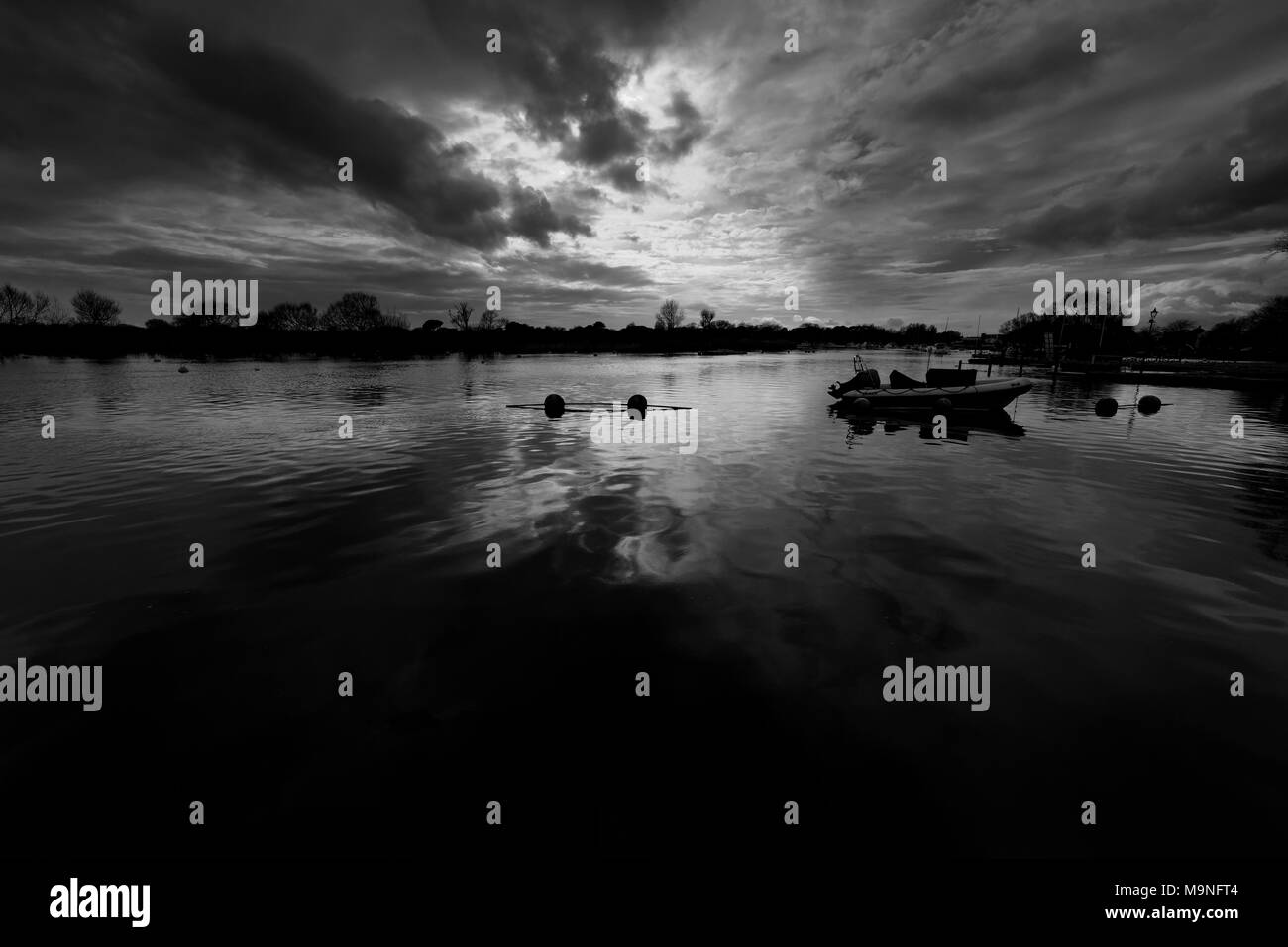 Winter scene on the River Stour at CHristchurch in Dorset with approaching storm clouds reflected in the calm river water Stock Photo