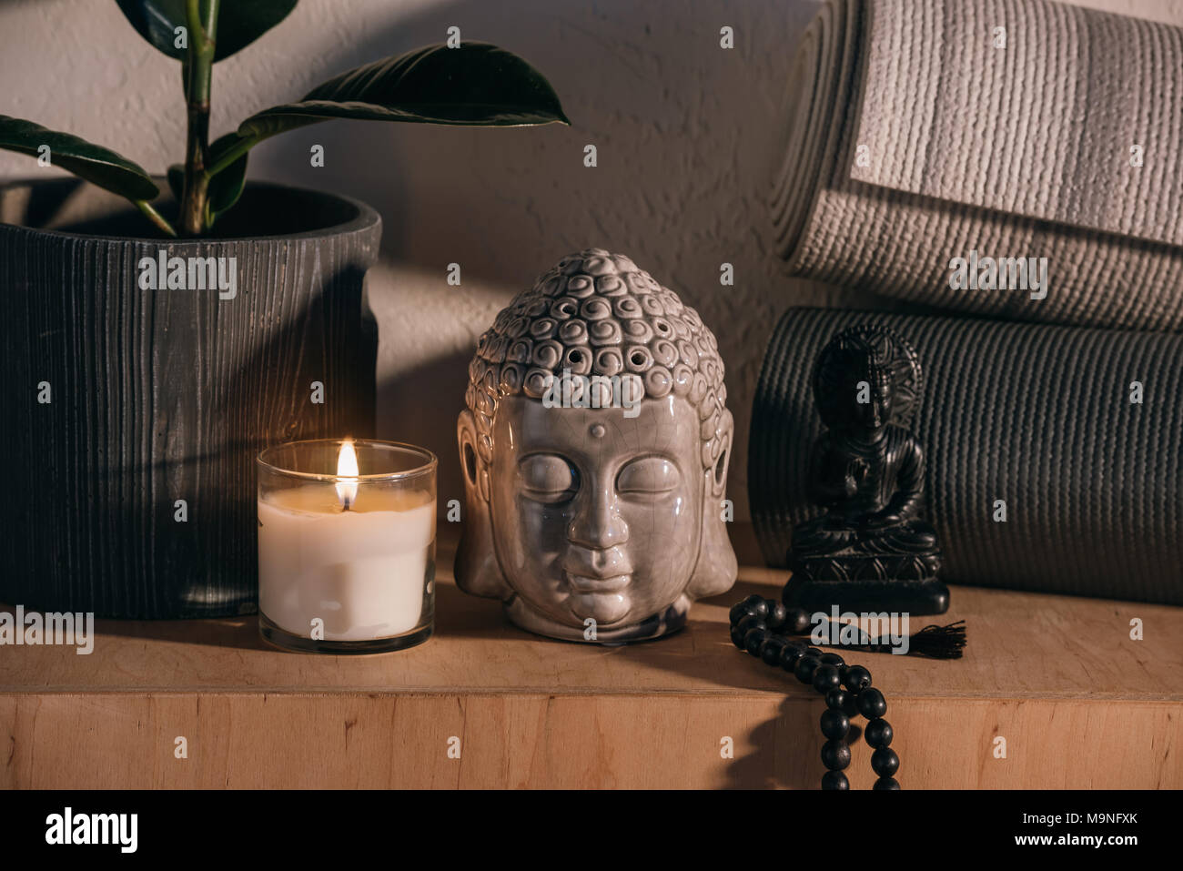 sculptures of buddha and yoga mats on wooden shelf  Stock Photo