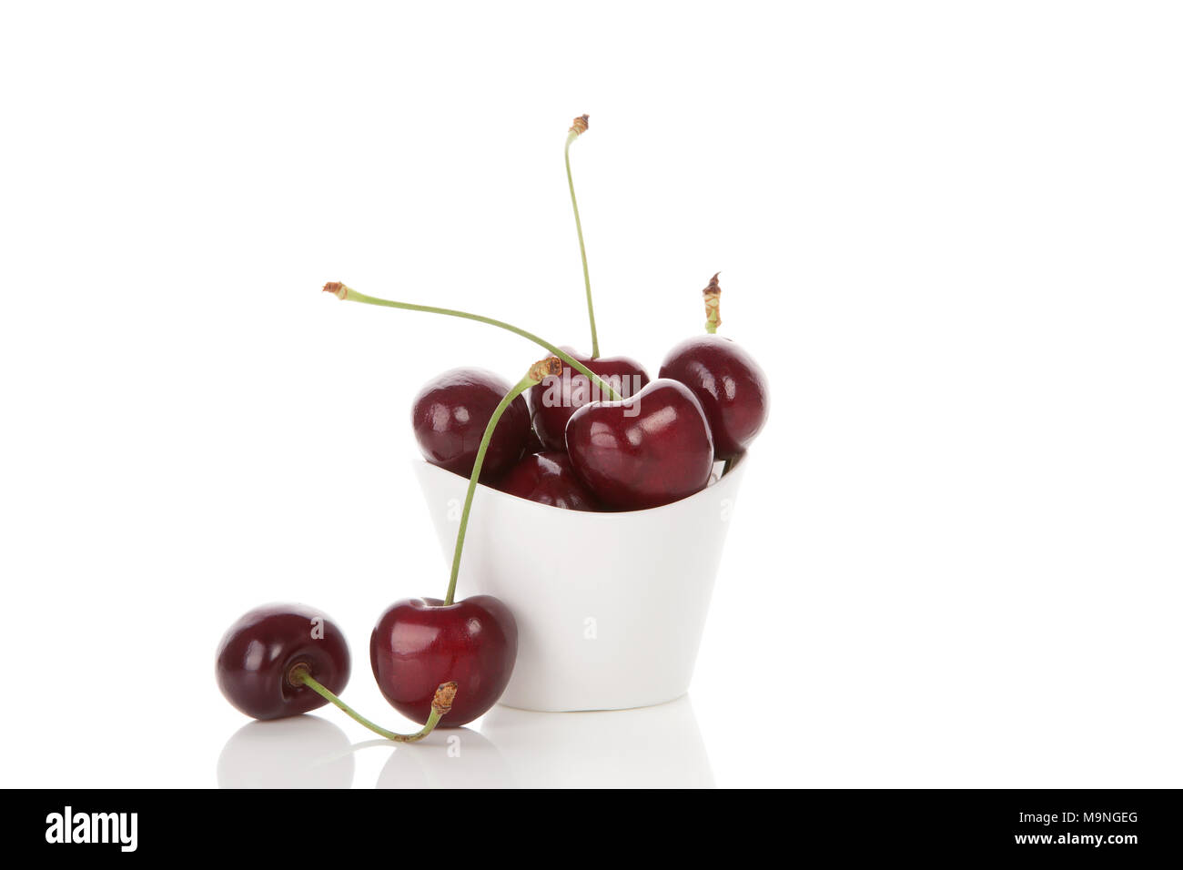 Delicious ripe cherries in white cup with reflection isolated on white ...