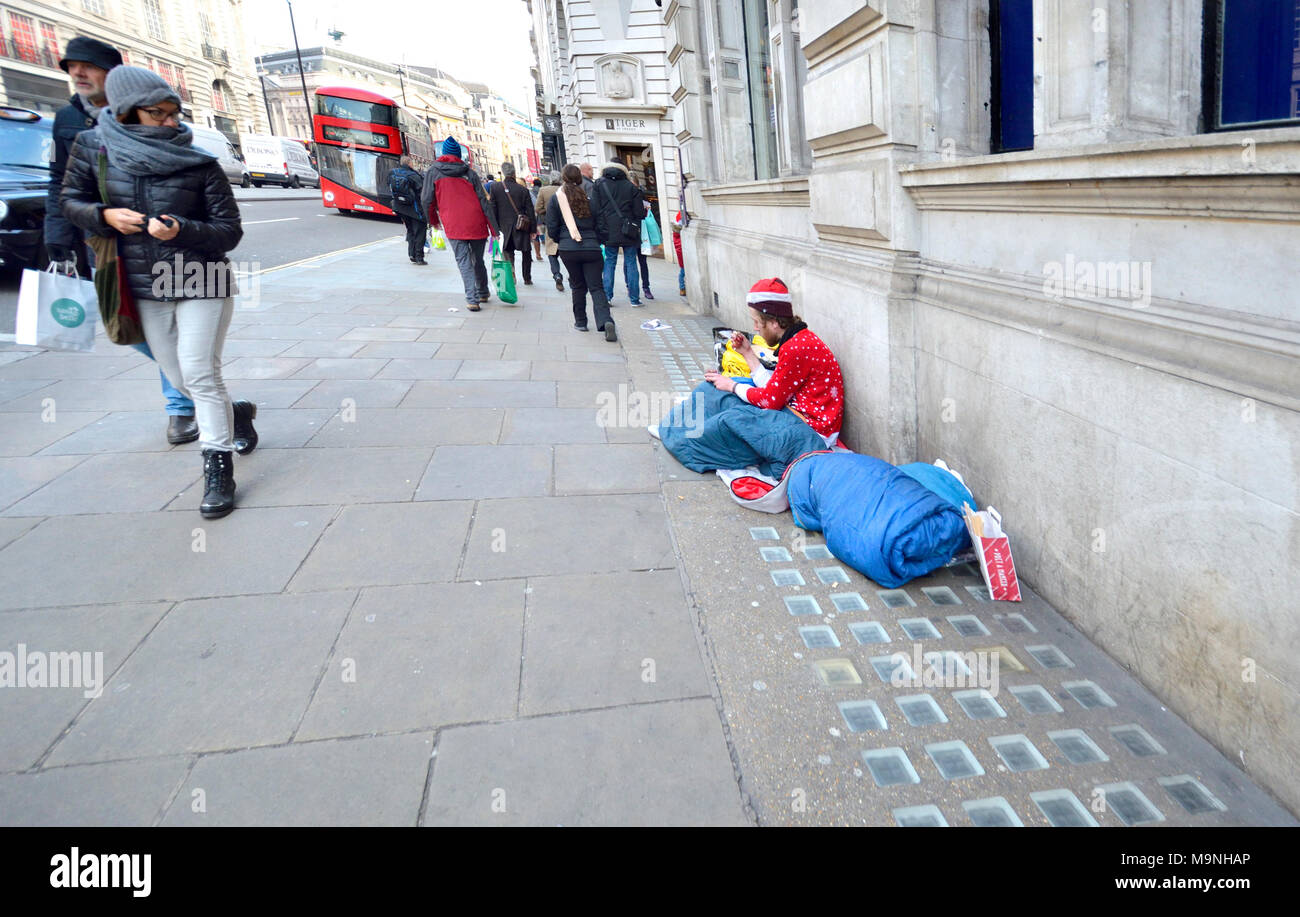 London, England, UK. Homeless man at Christmas in Piccadilly wearing Santa hat and Xmas jumper Stock Photo