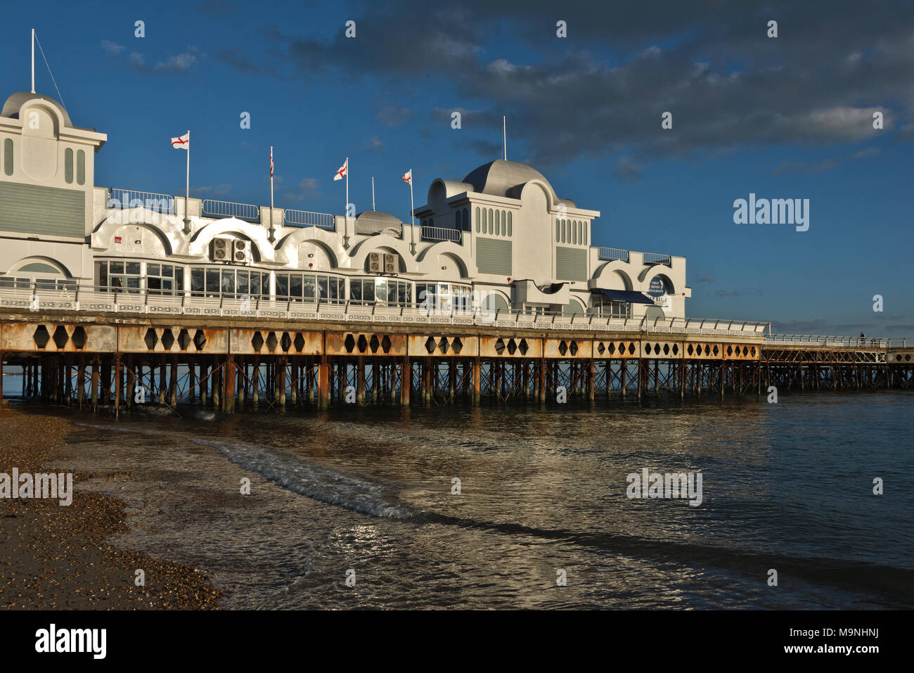 side view of Portsmouths South Parade Pier in Southsea, England, side lit on a calm day with England flags blowing in the breeze Stock Photo