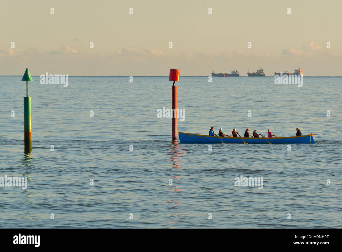 Rowing Gig passing navigation pillars on the seafront near South Prade Pier, Southsea, Portsmouth,  on a calm sunny day with ships on the horizon Stock Photo