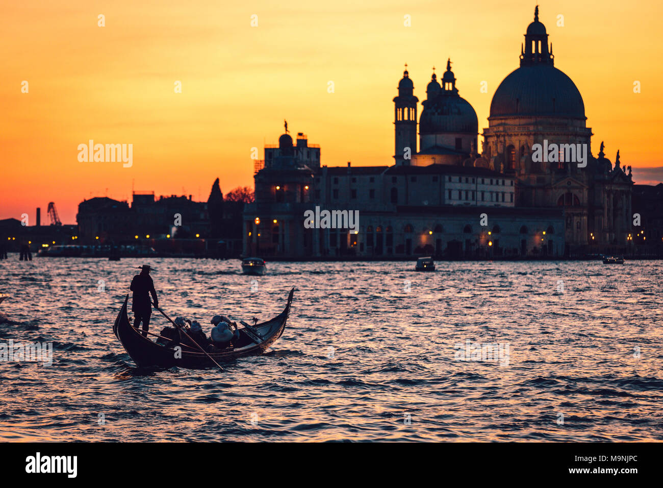 Venice (Italy) - Gondola in a golden sunset of Venice Lagoon with the background Basilica of Santa Maria della Salute Stock Photo