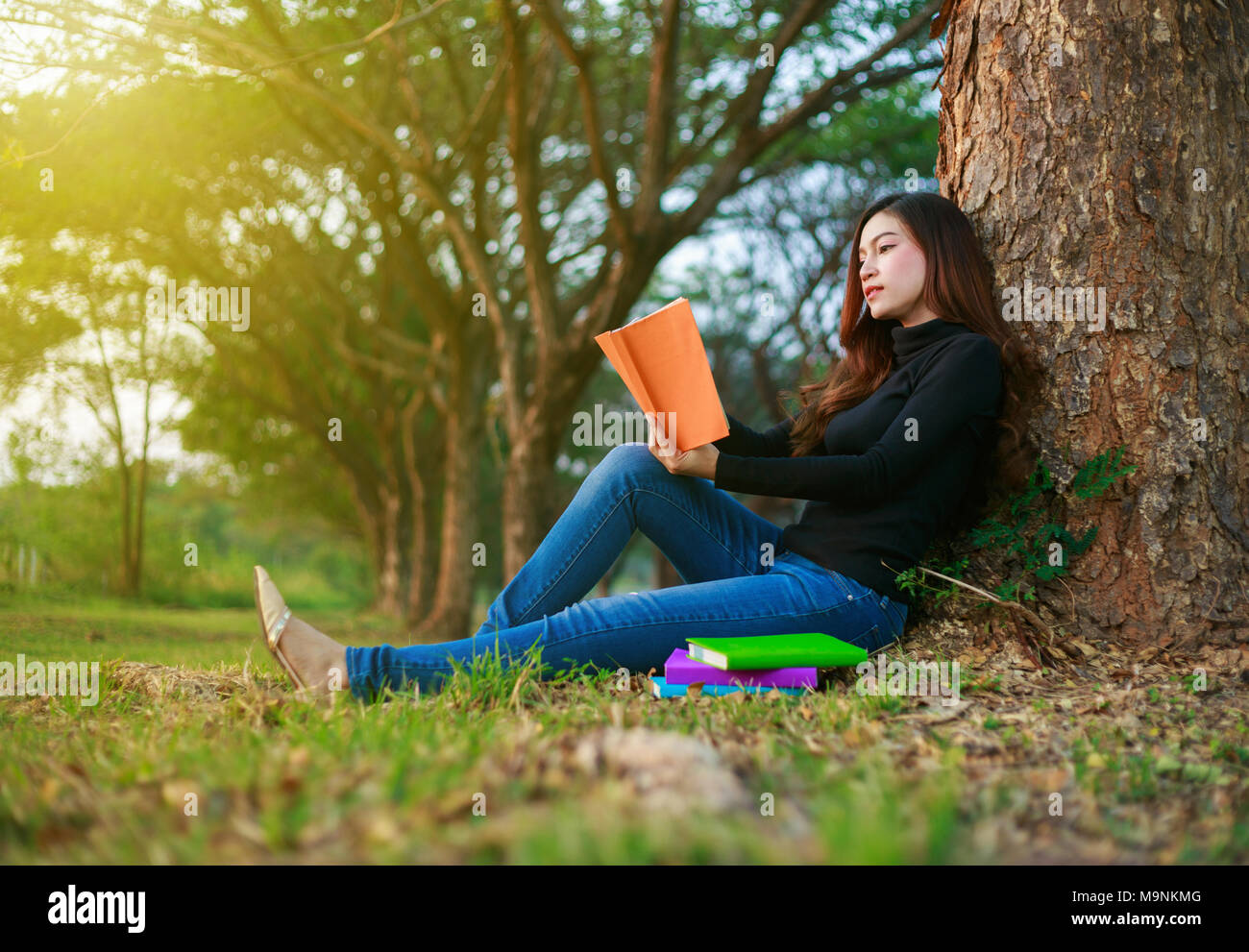 young woman sitting and reading a book in the park Stock Photo - Alamy