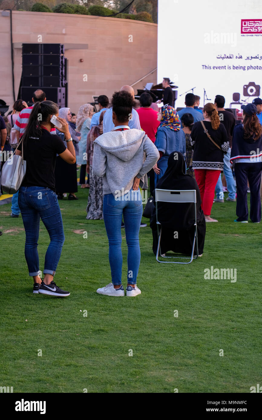 Young girls wearing tight jeans, enjoying music at live outdoor concert in  Umm Al Emarat Park, Abu Dhabi, UAE Stock Photo - Alamy