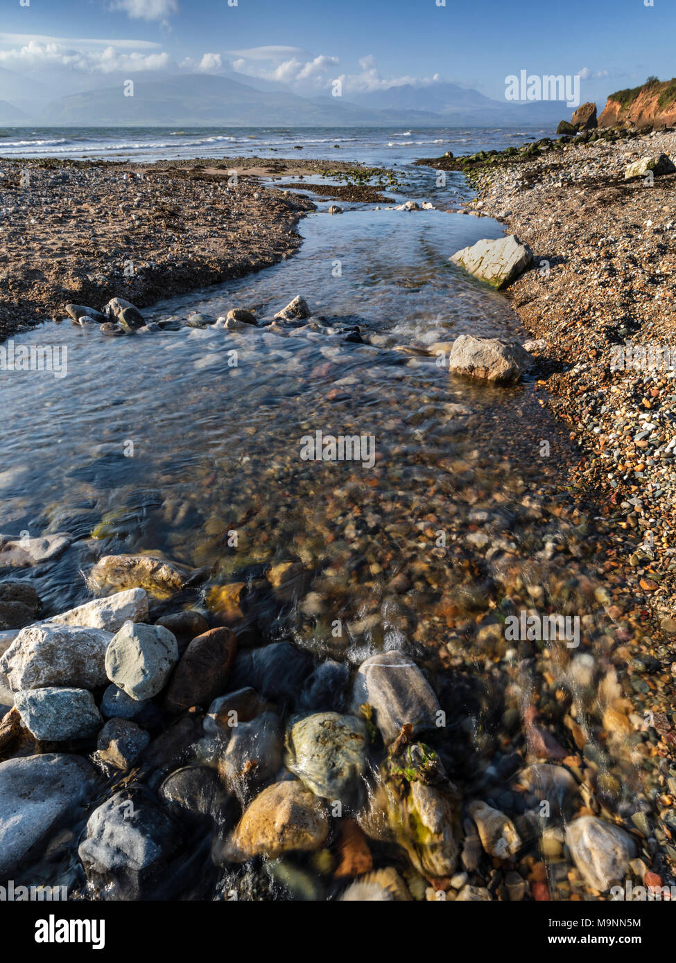 A stream flowing into the Menai Stait at Lleiniog Beach, Anglesey, North Wales UK Stock Photo