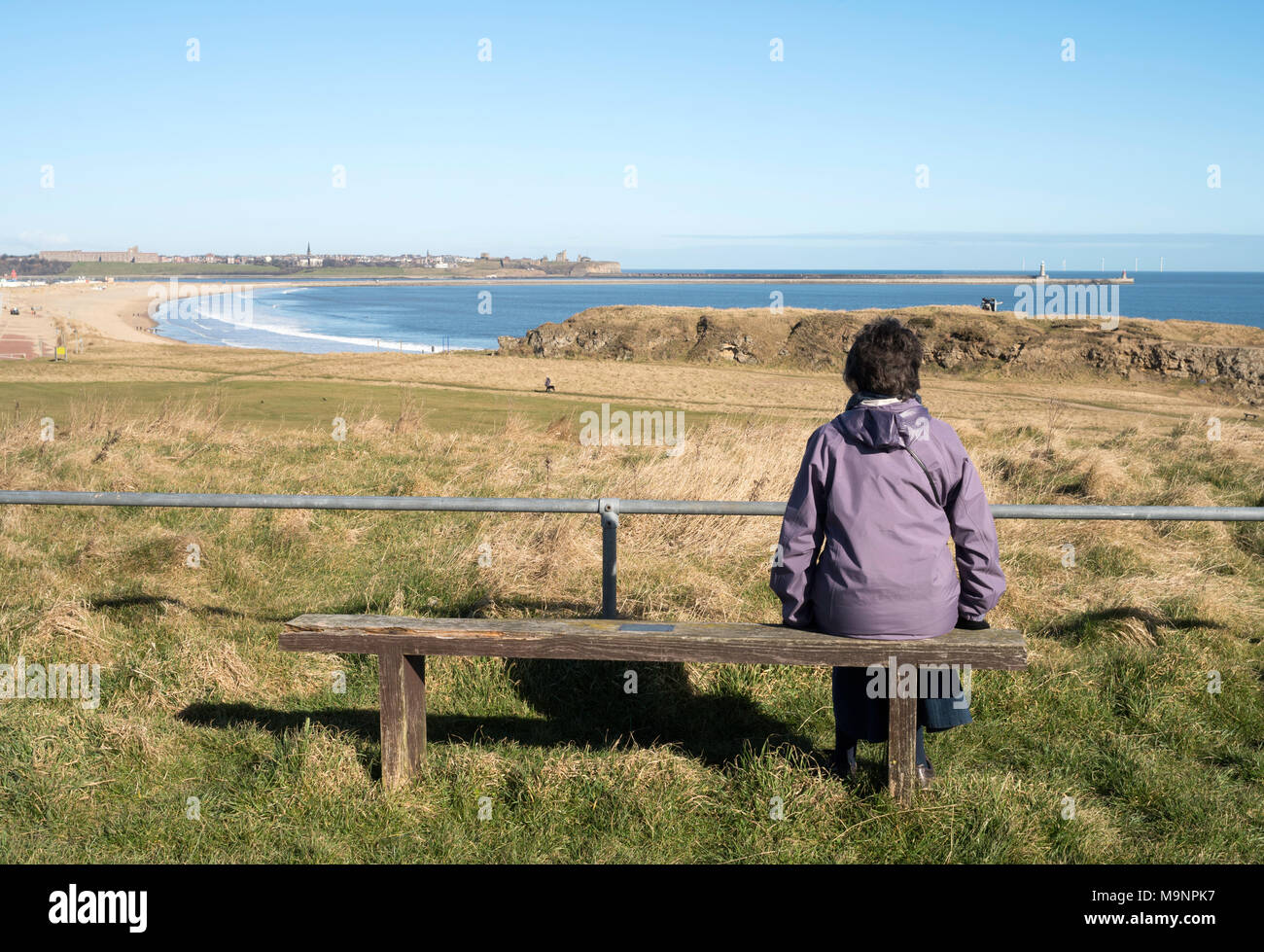 Woman sitting looking across the Tyne estuary from South Shields towards Tynemouth, north east England, UK Stock Photo