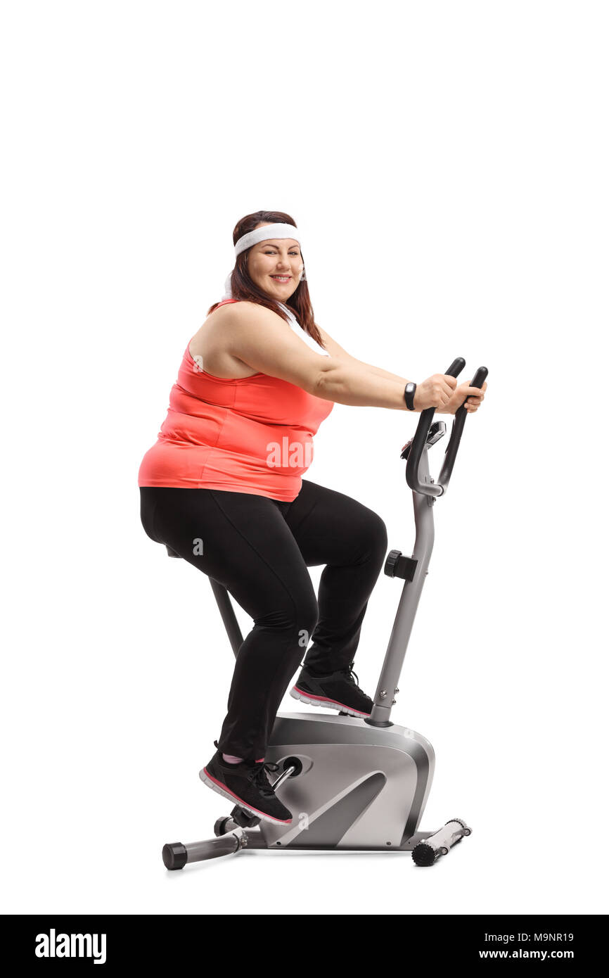 Overweight woman exercising on a stationary bike and looking at the camera isolated on white background Stock Photo