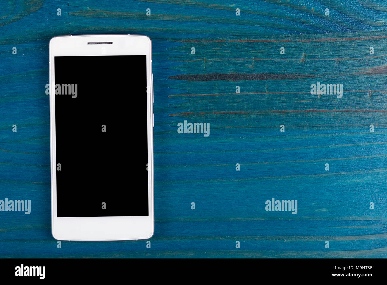 A white smartphone with black screen isolated on wood painted blue. Stock Photo