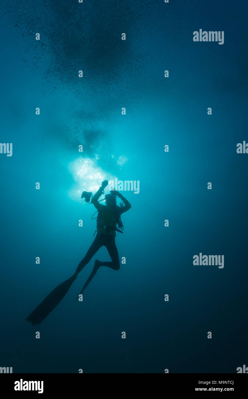 Silhouette of scuba diver ascending to surface after dive Stock Photo