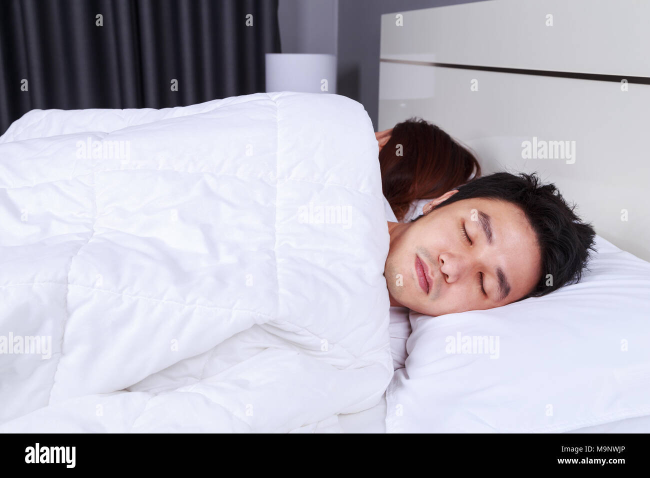 sick young man sleeping on bed with his wife Stock Photo