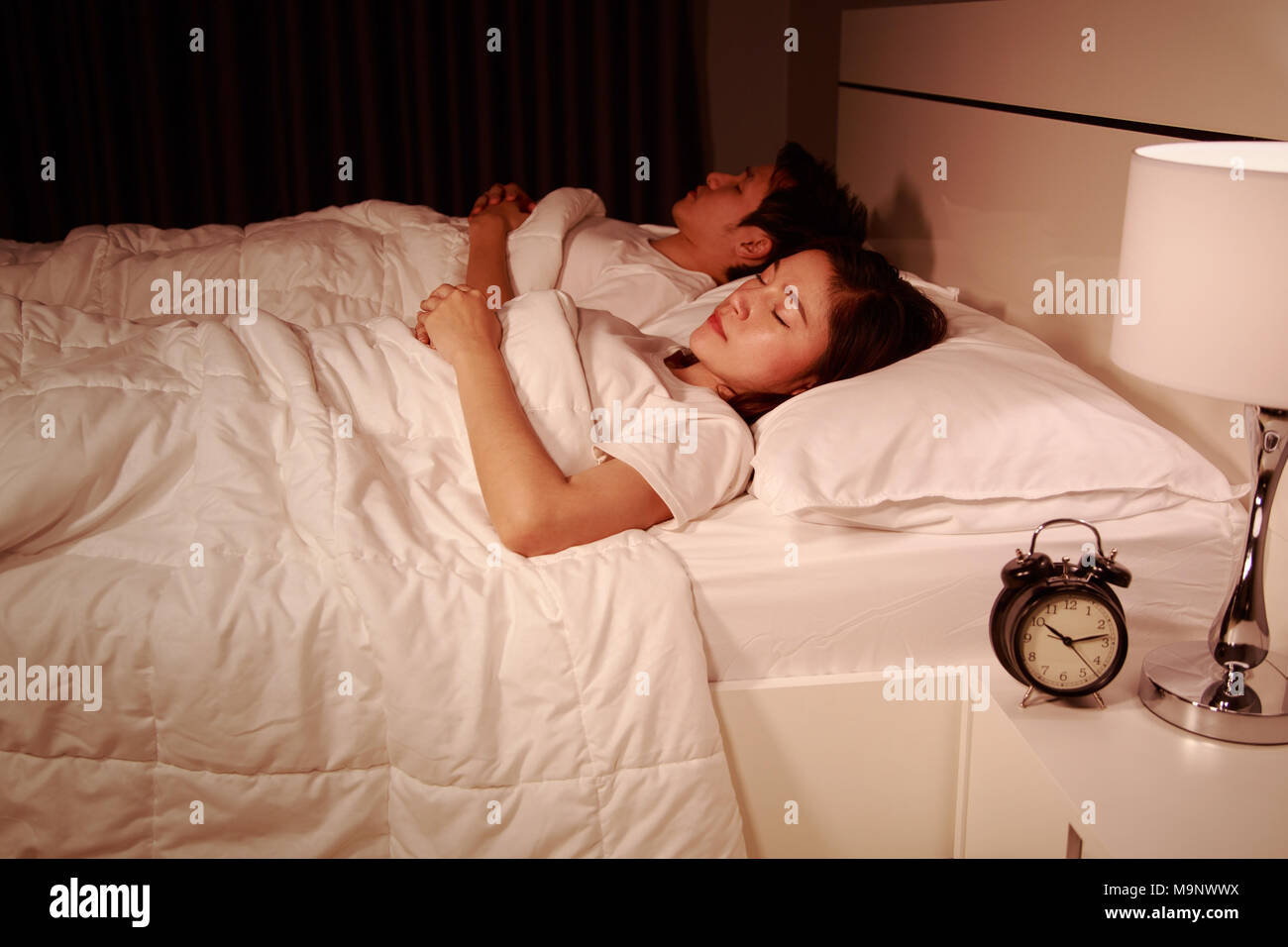 young couple sleeping on a comfortable bed in bedroom at night Stock Photo
