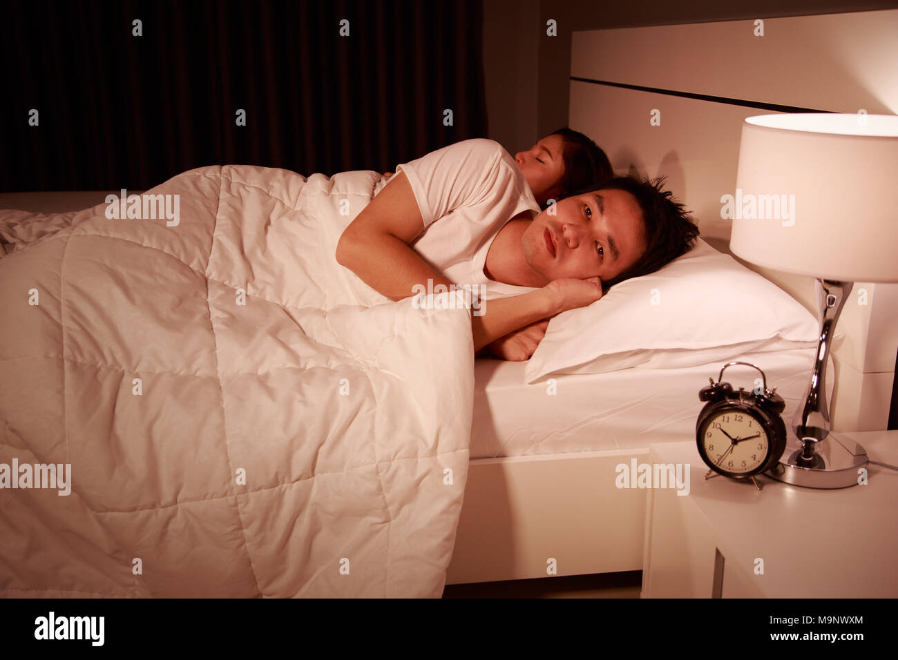 man having sleepless on bed and having migraine,stress, insomnia, hangover in the bedroom at night Stock Photo