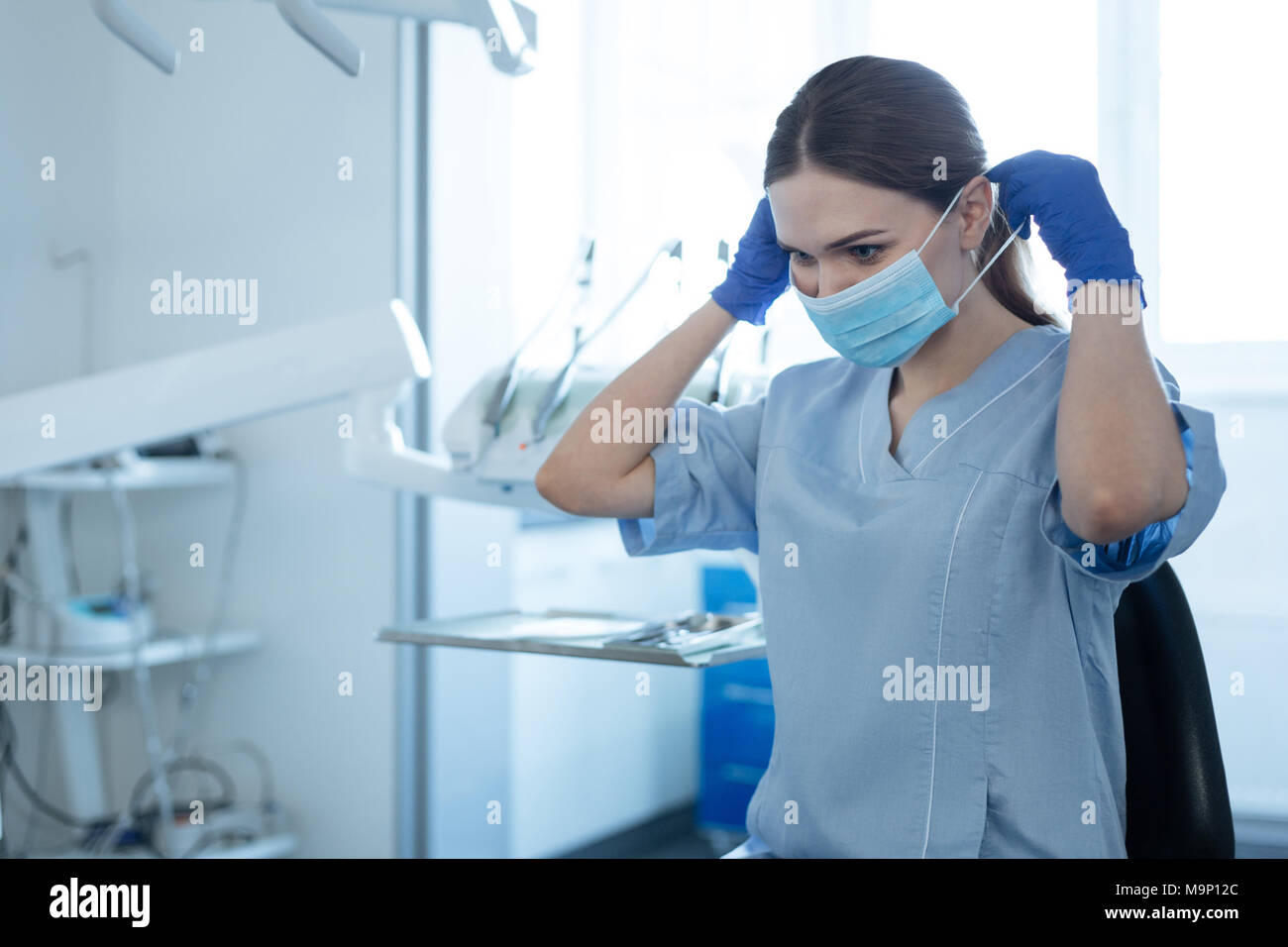 Pretty female dentist putting on a face mask before work Stock Photo