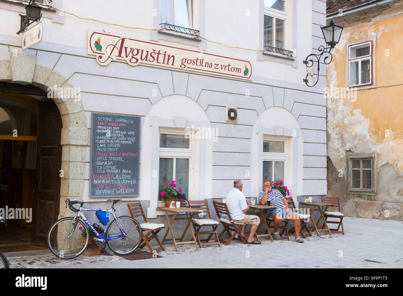 Locals hanging out on terrace of cafe on Linhartov Trg, the colorful main square of Radovljica, Slovenia Stock Photo