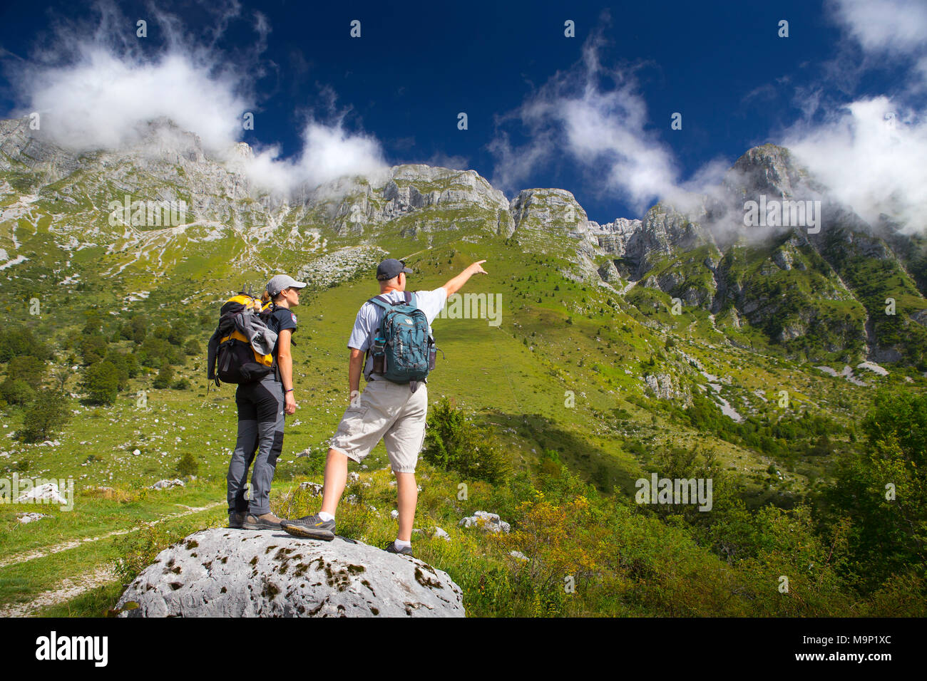 Two hikers looking at peaks of Krn mountain range in Triglav National Park, Slovenia Stock Photo