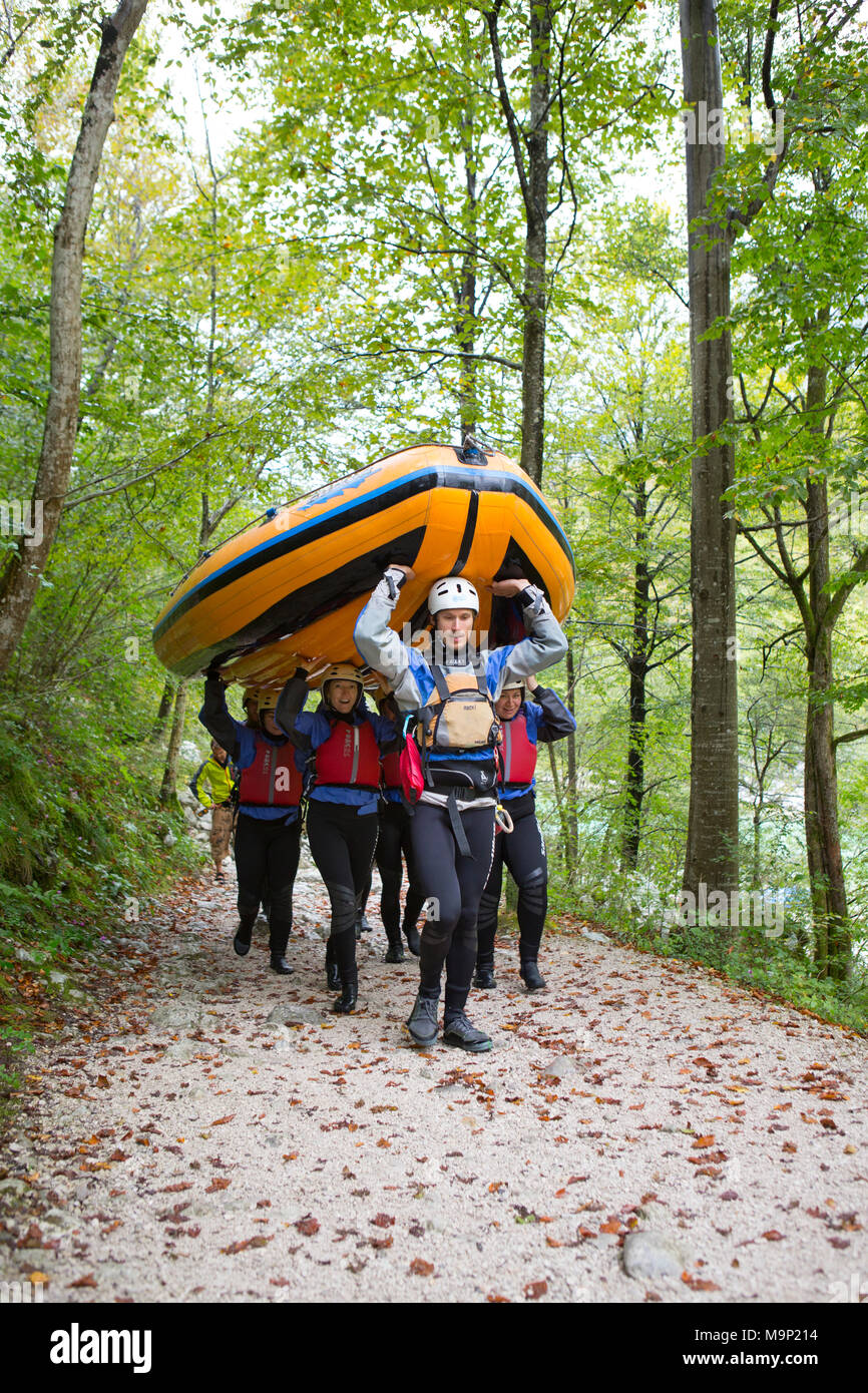 Group of rafters carrying inflatable boat over their heads to river Soca near Bovec, Triglav, Slovenia Stock Photo