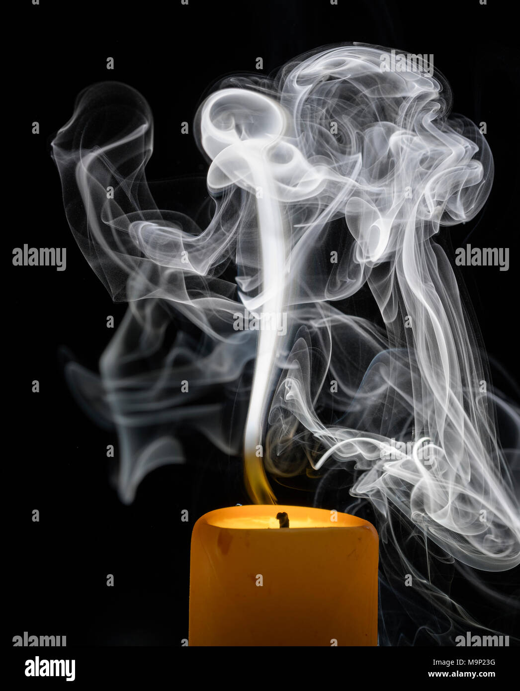 Smoky candle in front of a black background, studio shot Stock Photo