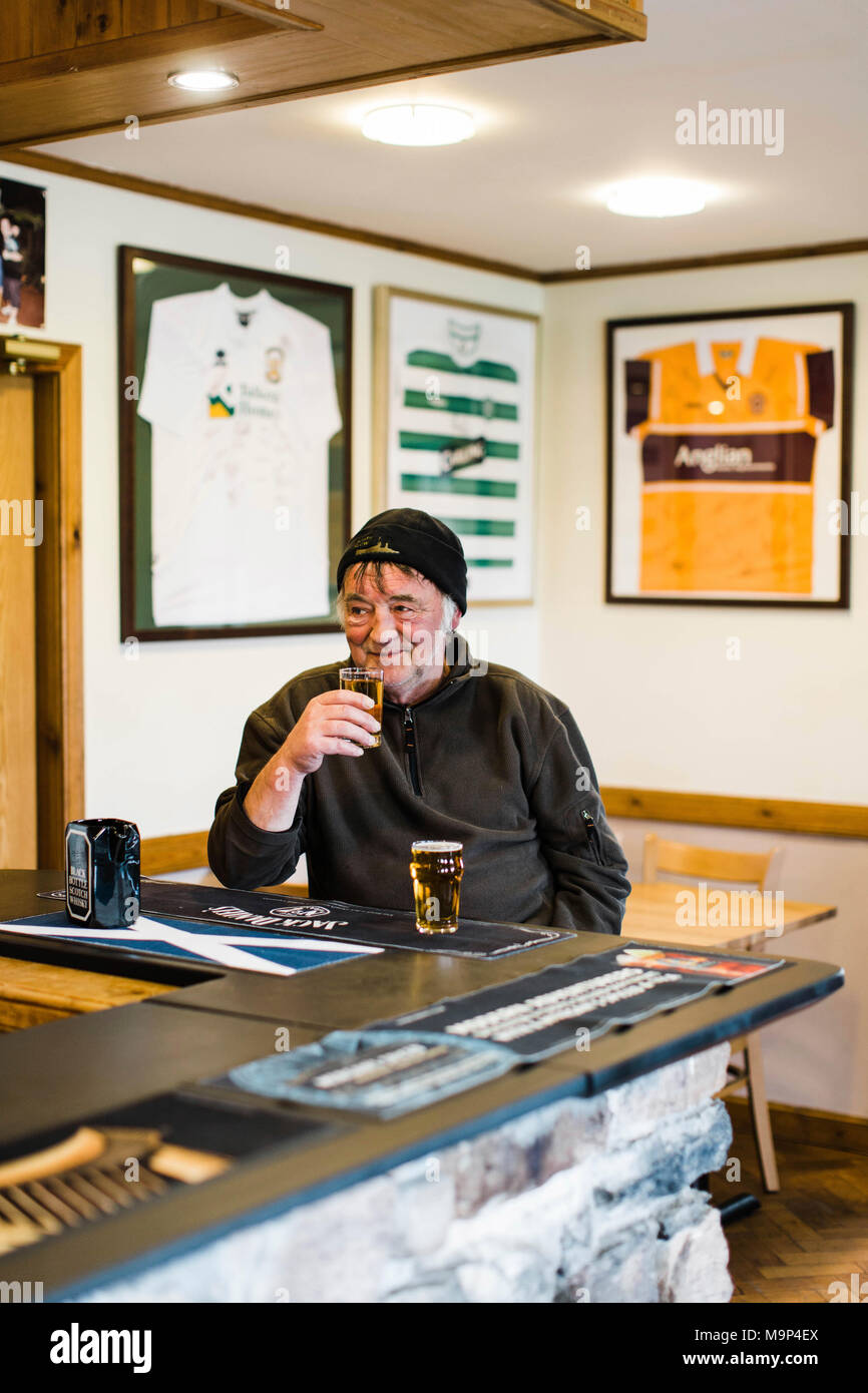 Older man enjoying beer beside counter at pub, Scotland, UK Stock Photo