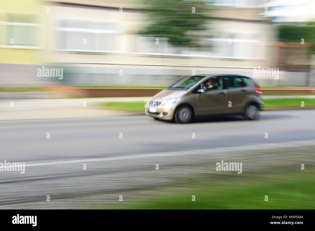 Car minivan drives through residential area, motion blur, Germany Stock Photo