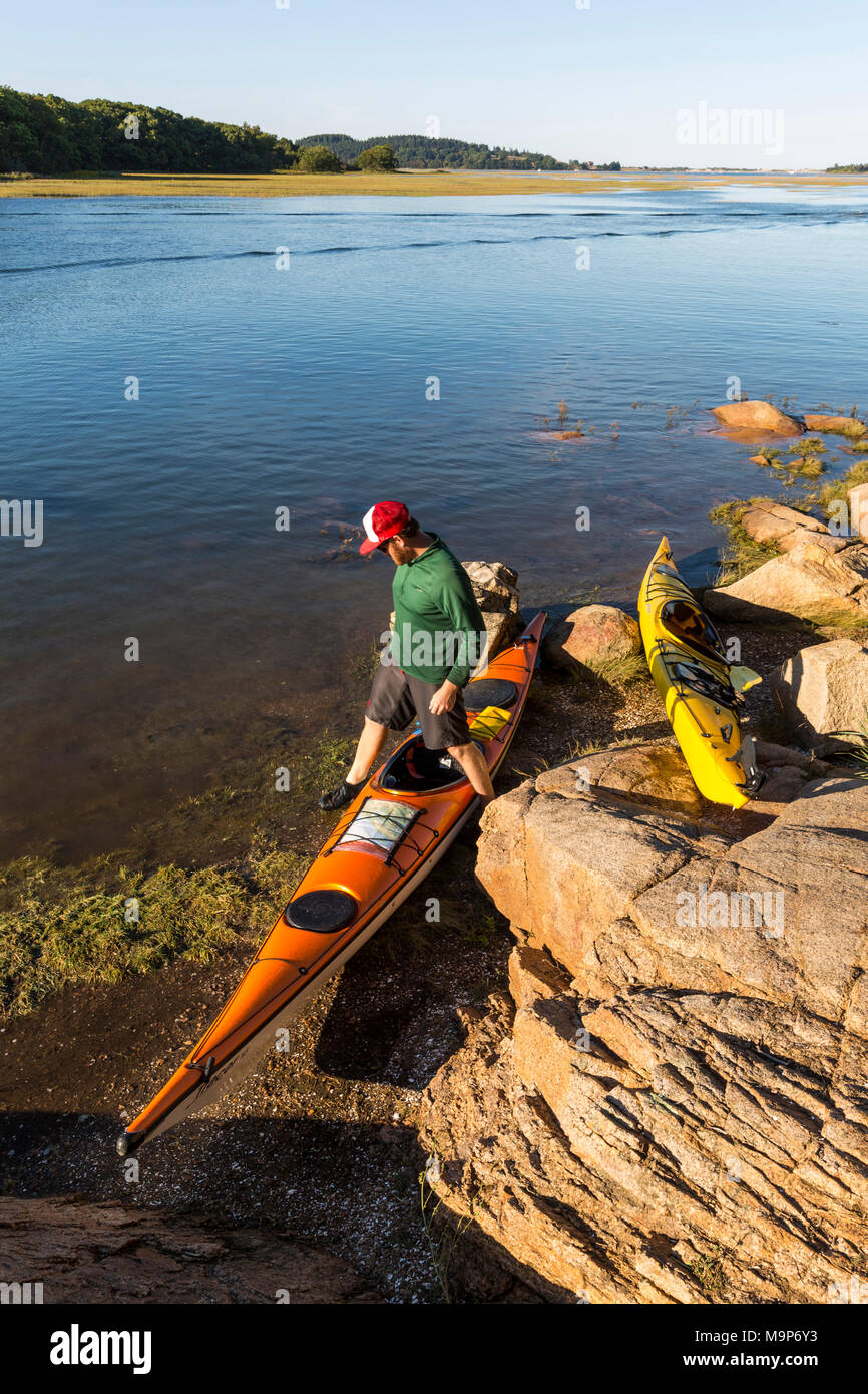 Man and pair of kayaks next to Essex River at Cox Reservation in Essex, Massachusetts Stock Photo