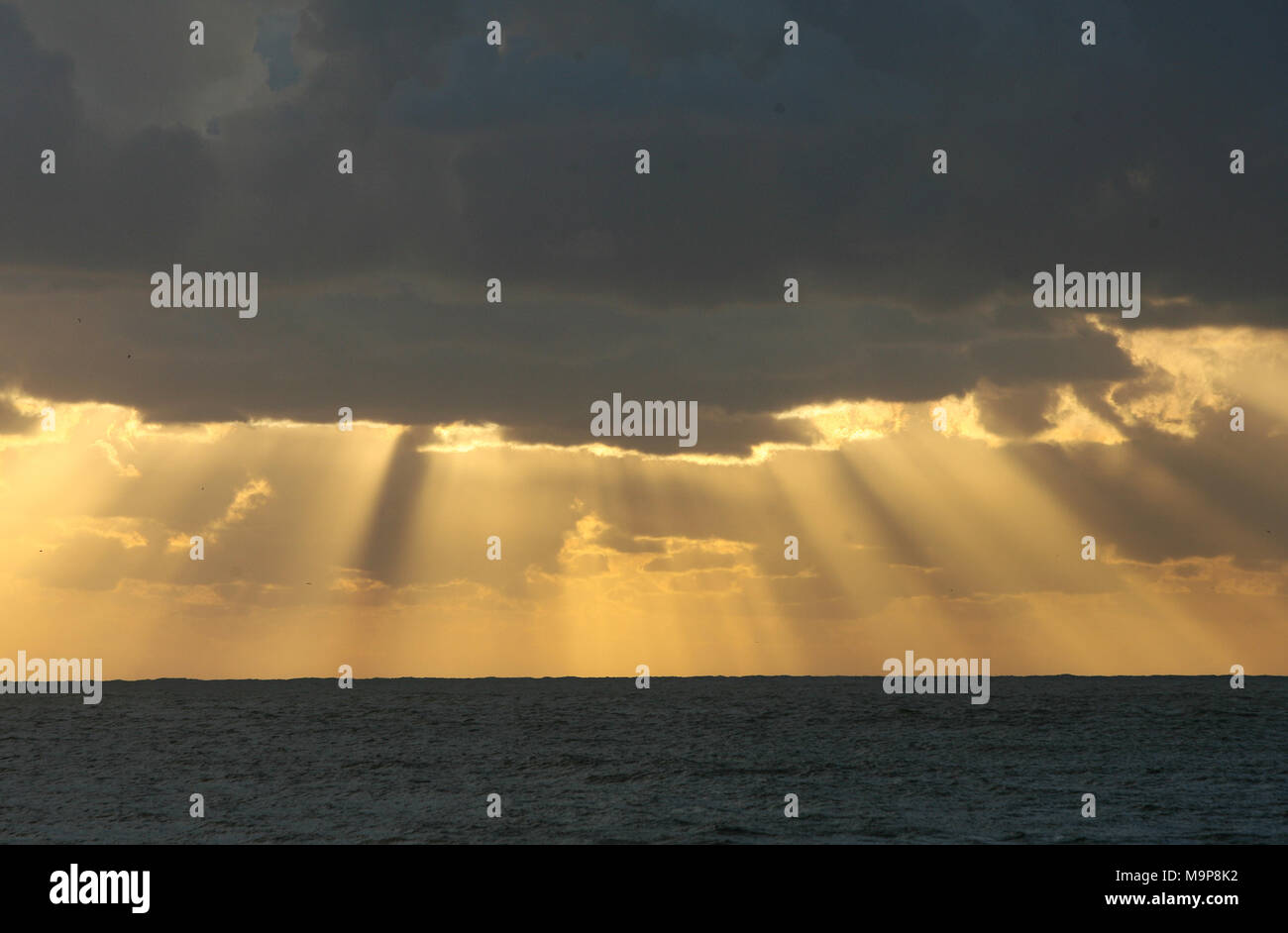 Sun rays through the clouds in the sea Stock Photo - Alamy