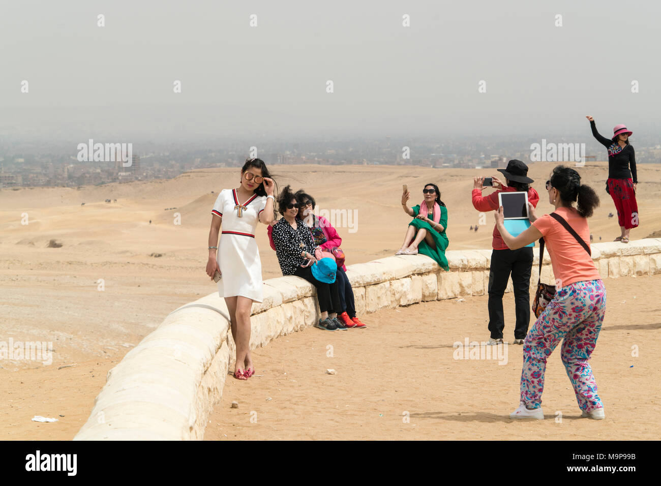 Female tourists posing and taking pictures at Giza pyramid complex