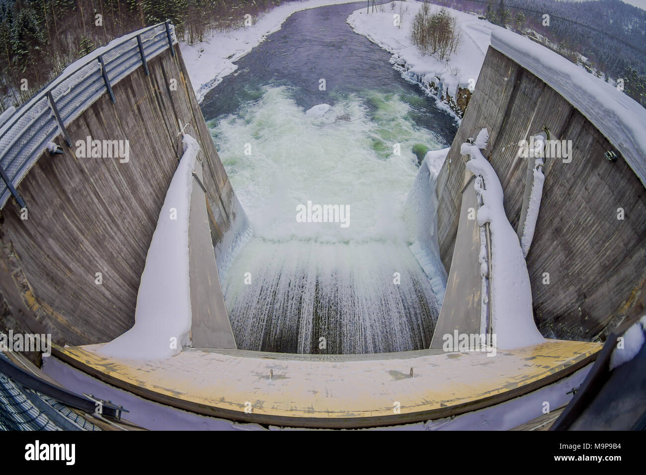 Above view of water reservoir with small dam. Small pile of snow and ice below the concrete dam. Location Hardangervidda in Norway Stock Photo