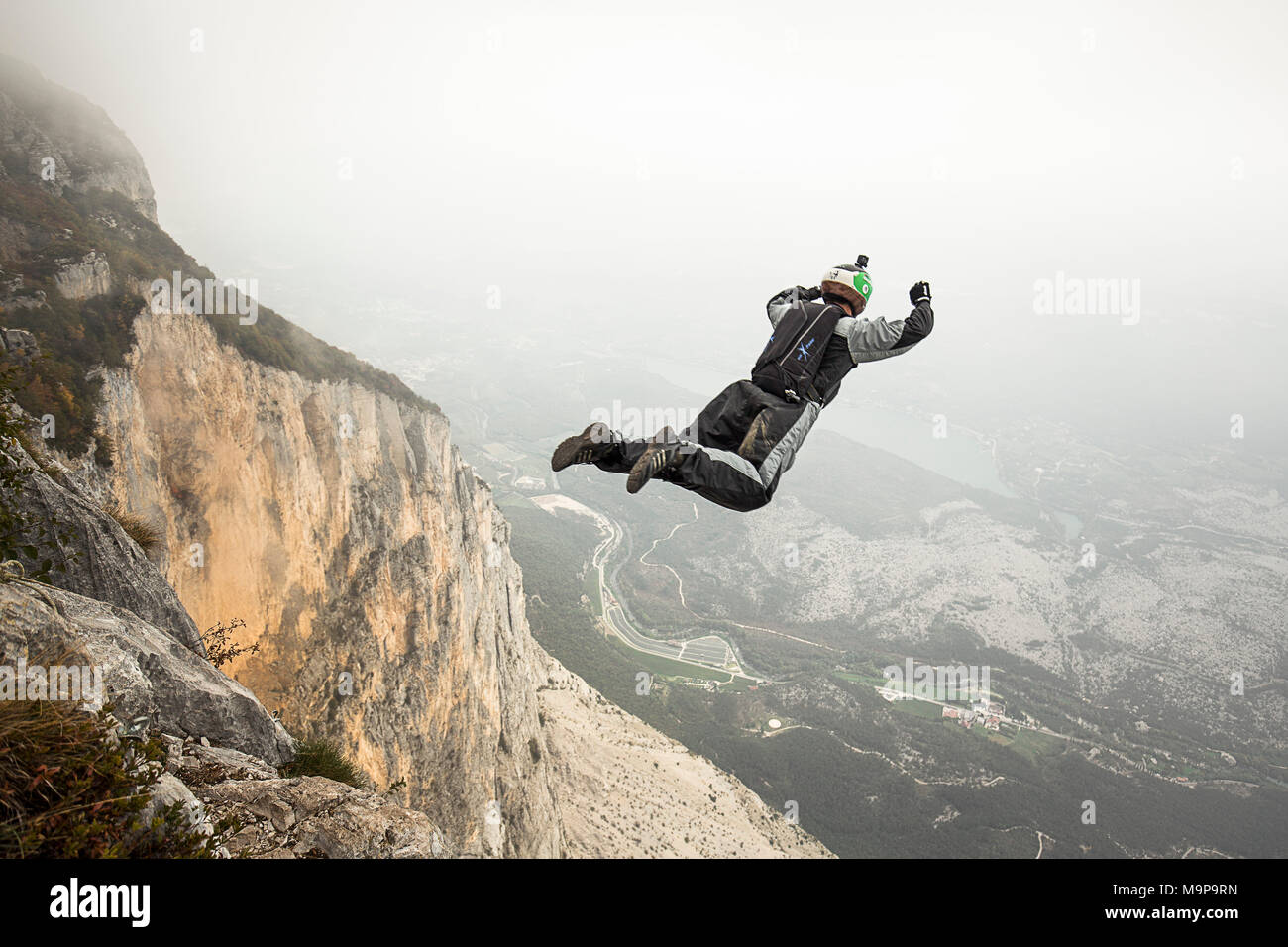 Base jumper mid air right after cliff jump during foggy weather, Brento, Venetien, Italy Stock Photo