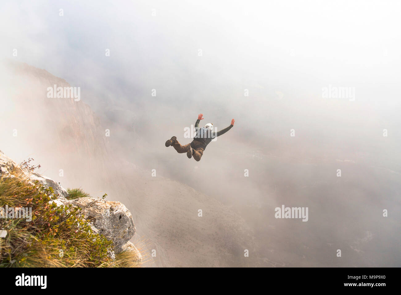 Base jumper mid air right after cliff jump during foggy weather, Brento, Venetien, Italy Stock Photo