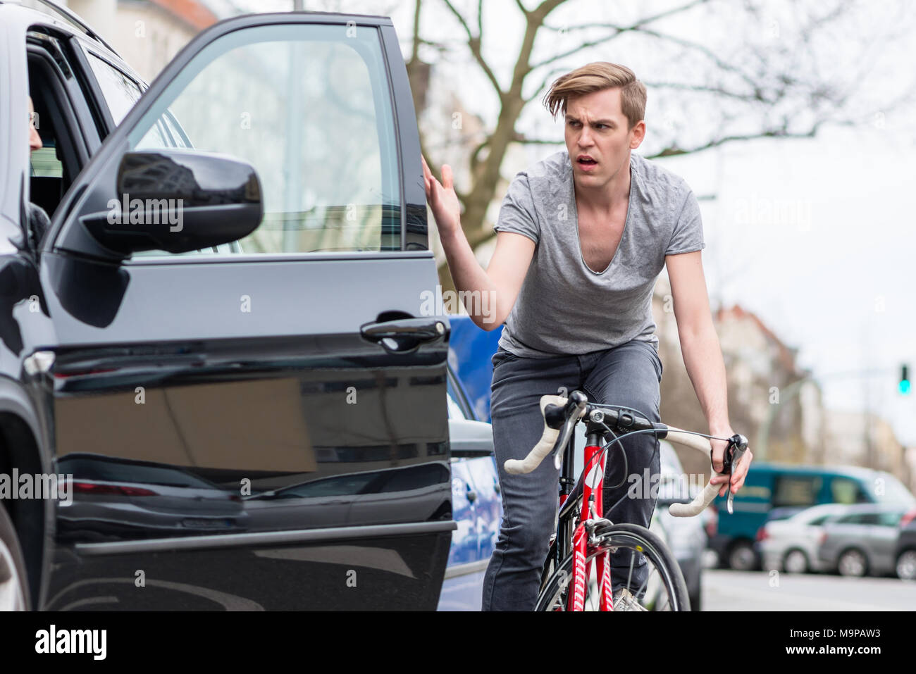 Young bicyclist shouting while swerving for avoiding dangerous collision Stock Photo