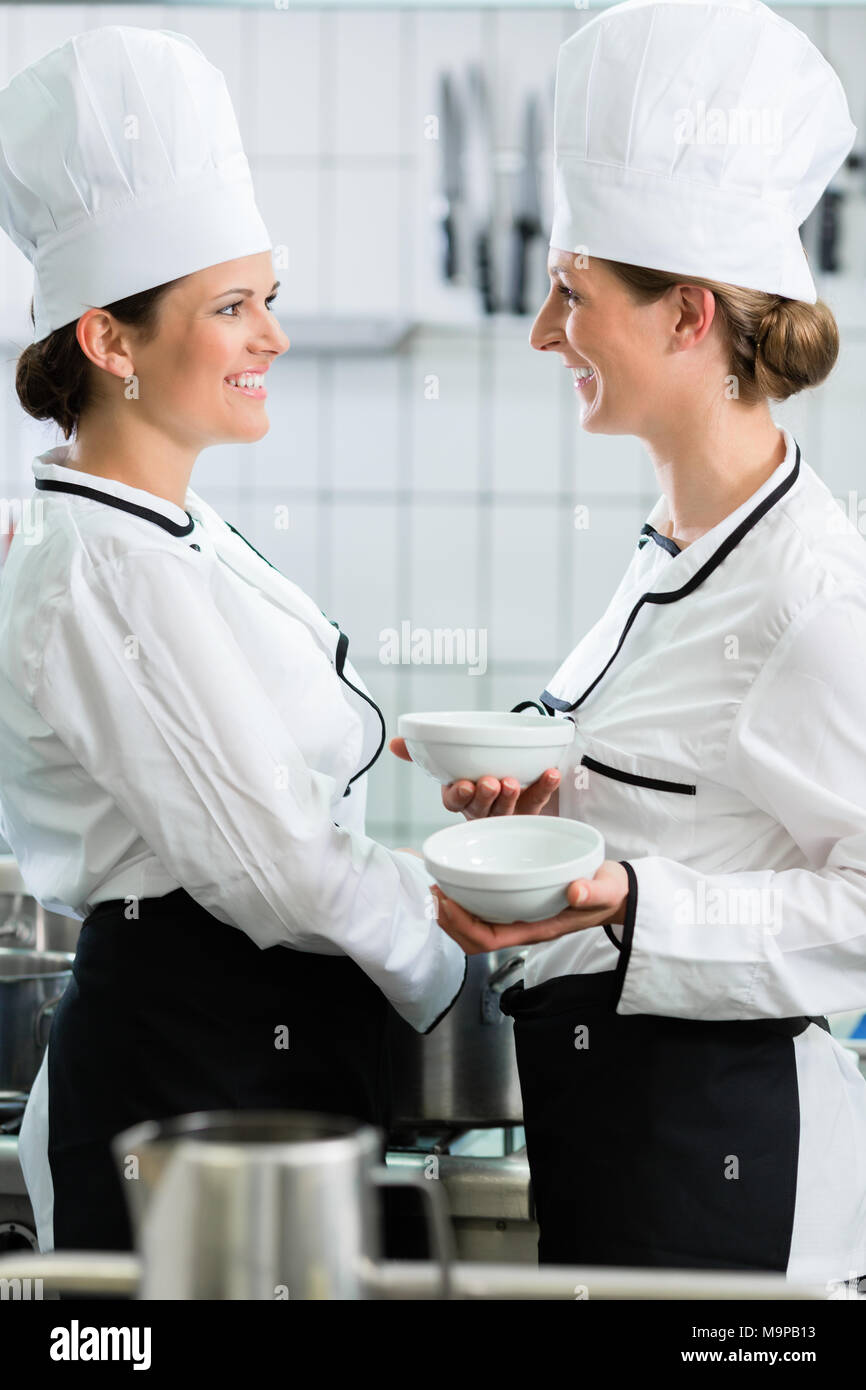 female chefs in commercial kitchen wearing white uniforms Stock Photo