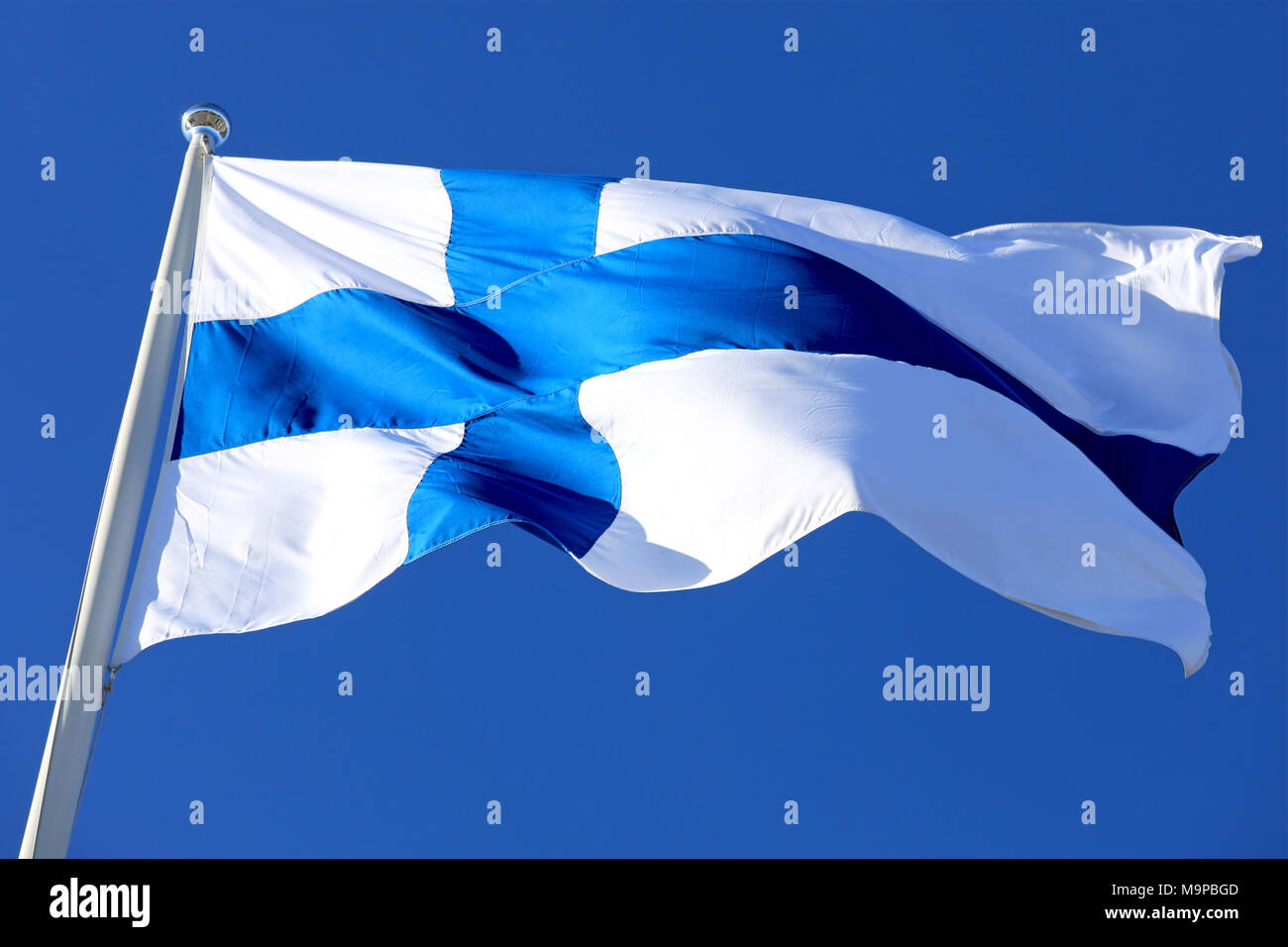 Flag of Finland flying against blue sky. Stock Photo