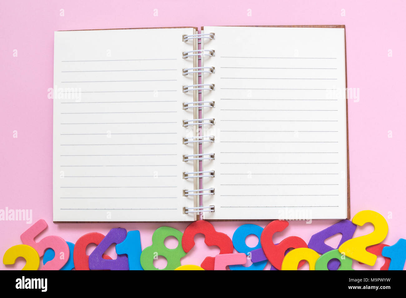 Open notepad and colorful numbers against pastel pink background flat ...
