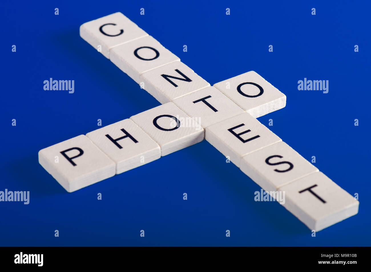 Photo Contest phrase made of white wooden blocks on blue background in crossword style Stock Photo