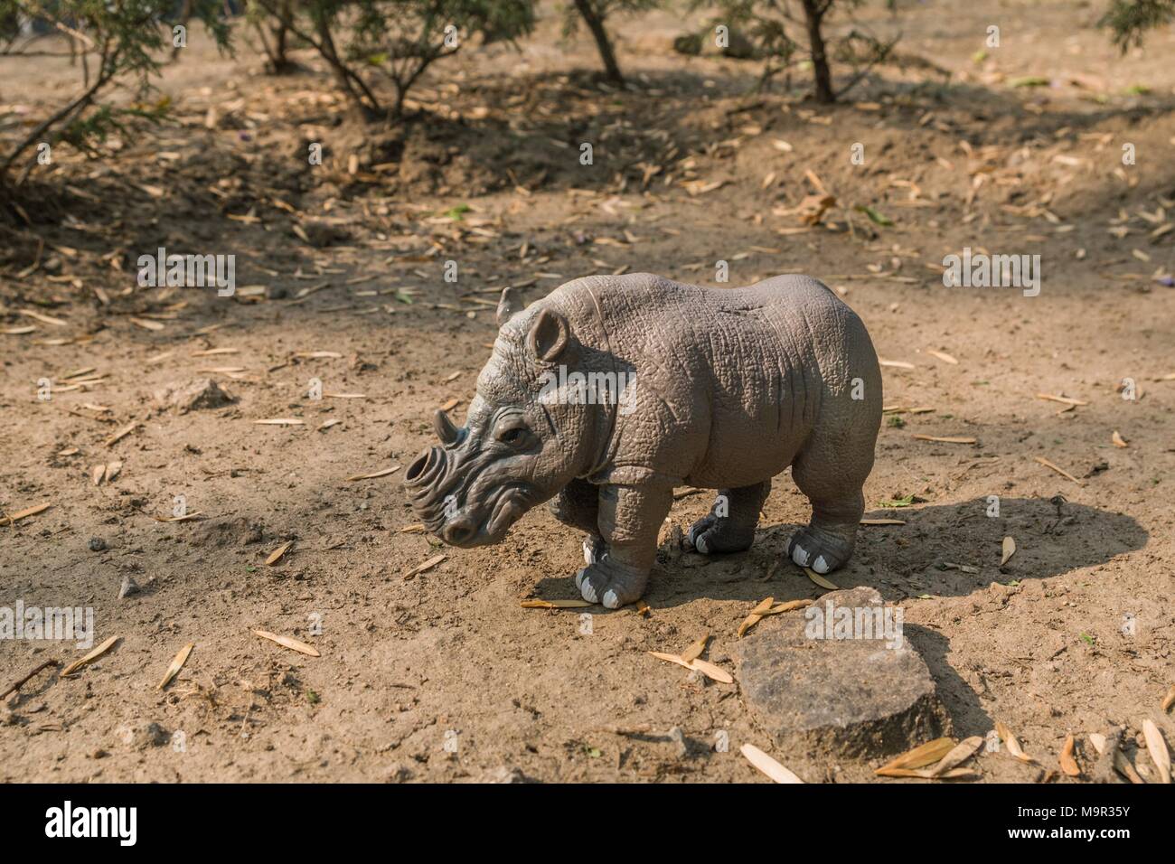 White toy rhino without a horn in a natural terrain. Stock Photo