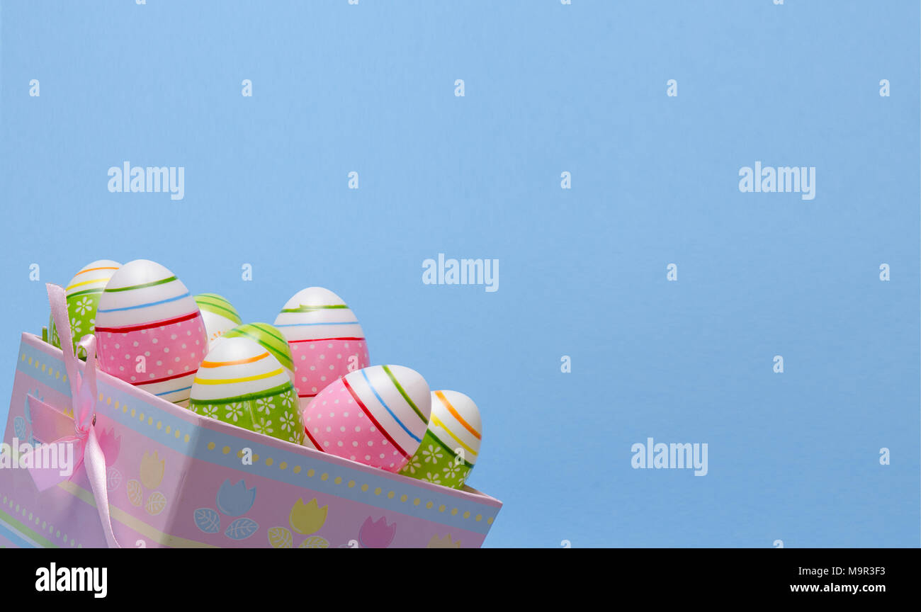 Colored Easter eggs in paper basket pastel colors on blue background. Easter theme. Stock Photo