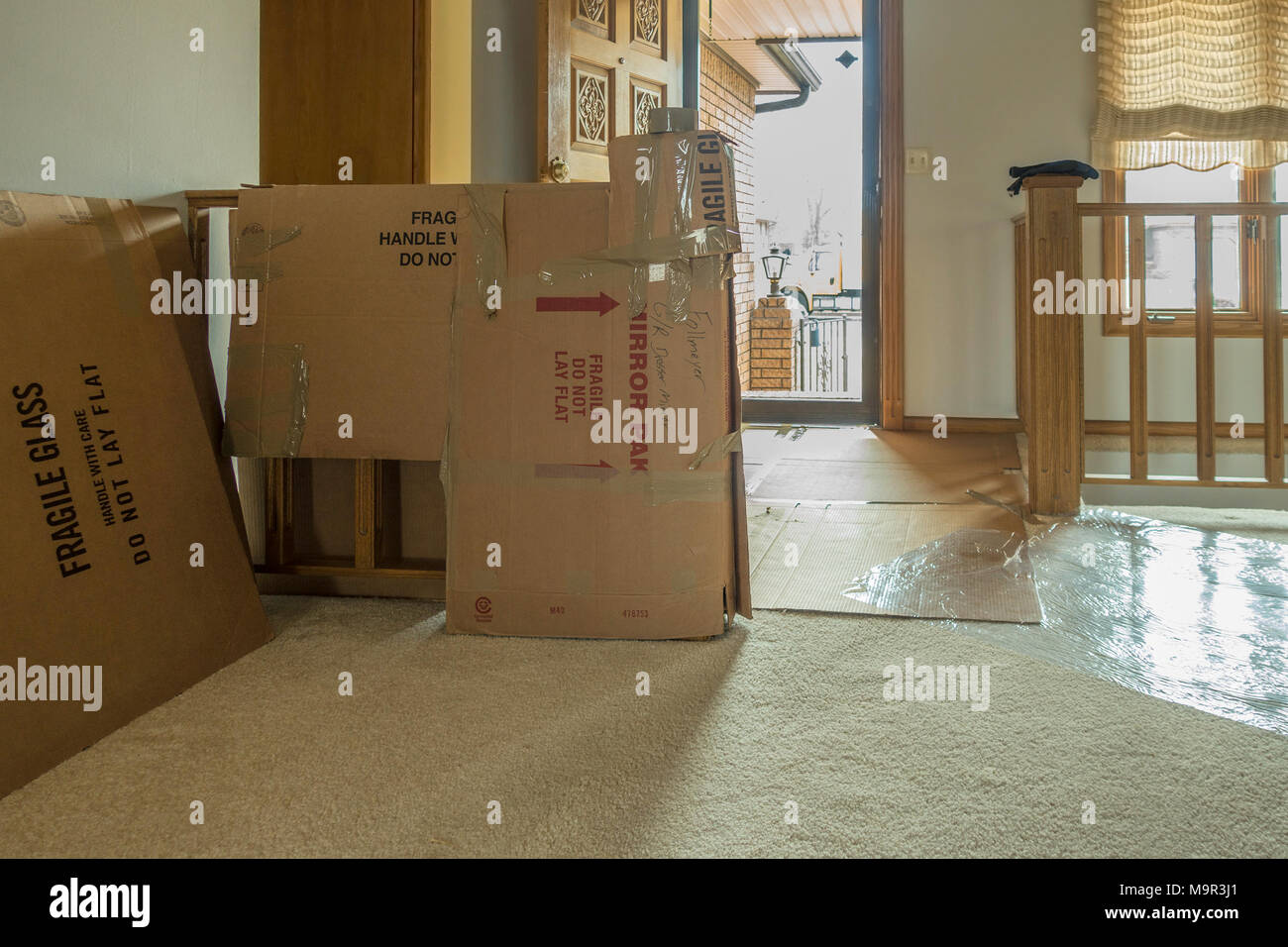 A home with protective plastic runners on the floor and cardboard boxes protecting woodwork  before moving furniture. Wichita, Kansas, USA. Stock Photo