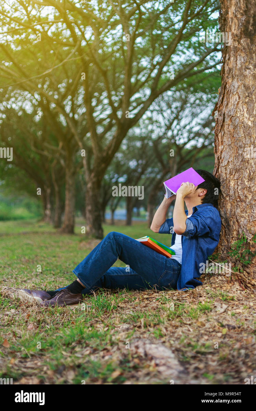 young man in stress situation when reading a book in the park Stock Photo
