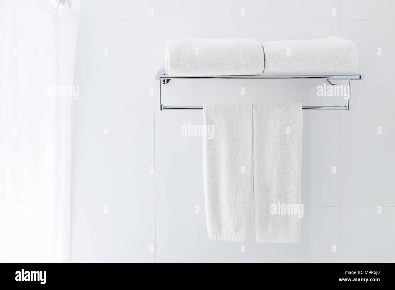 White bathroom towels hanging on the rack in a white bathroom near shower, good for clean and fresh theme or refresh concept Stock Photo