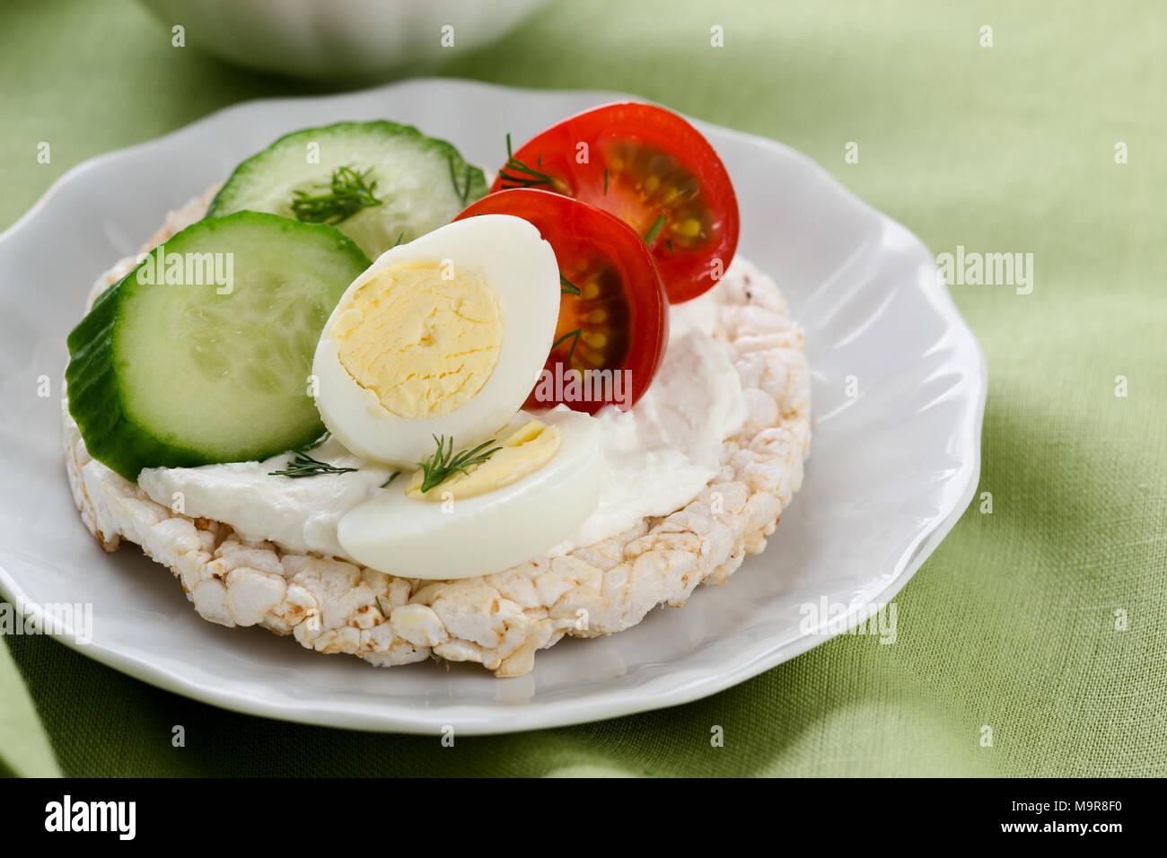 Open sandwiches of rice cakes with cream cheese , vegetables and quail egg, healthy breakfast